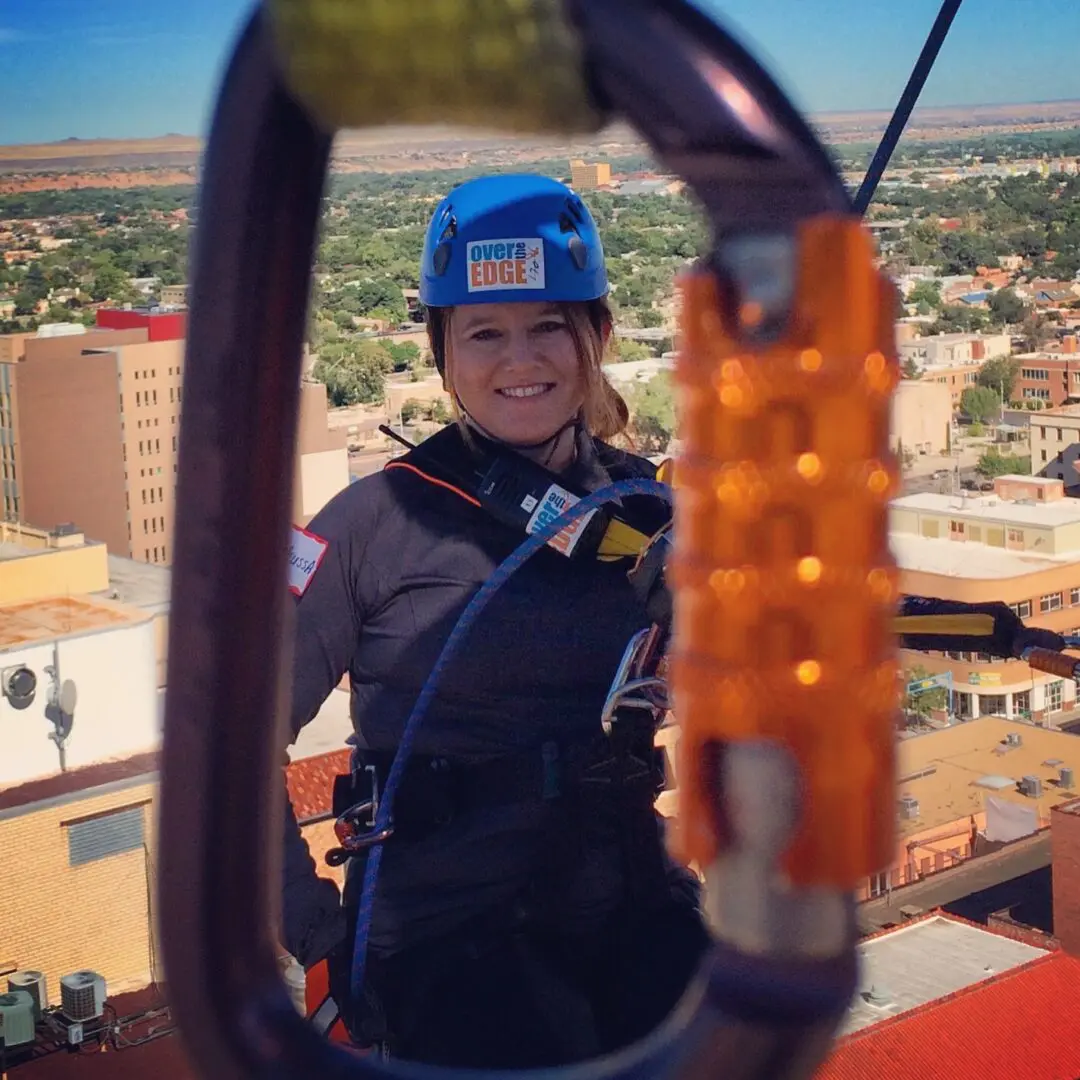 A woman in a blue helmet is on the side of a building.