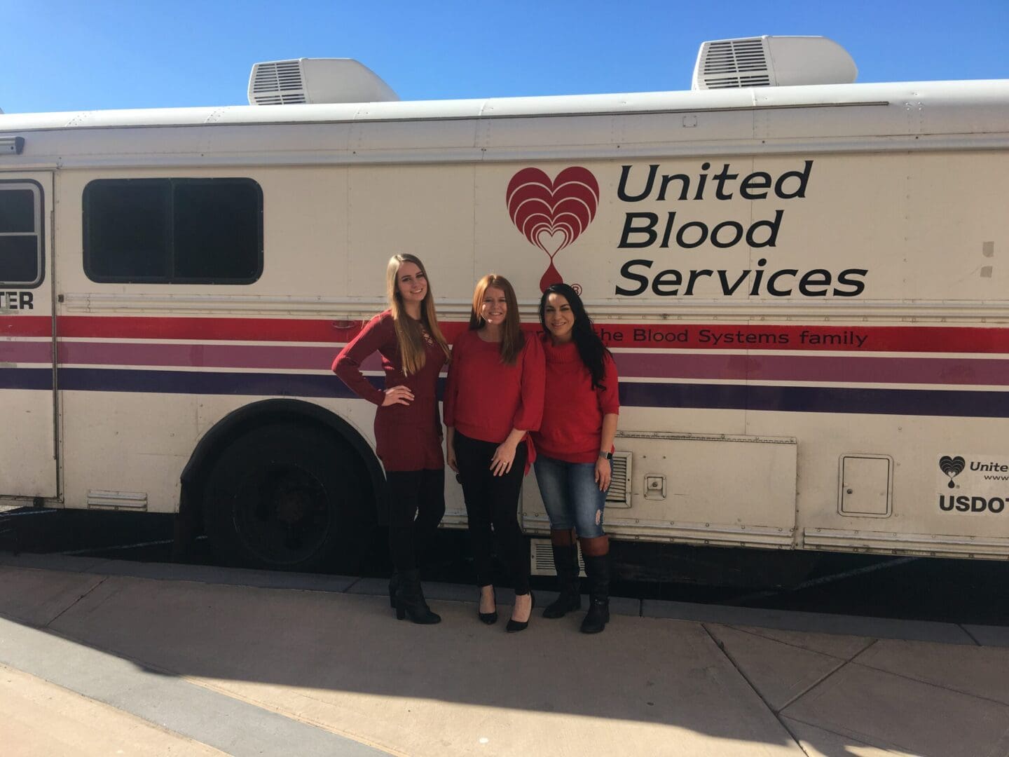 Three women standing in front of a bus.