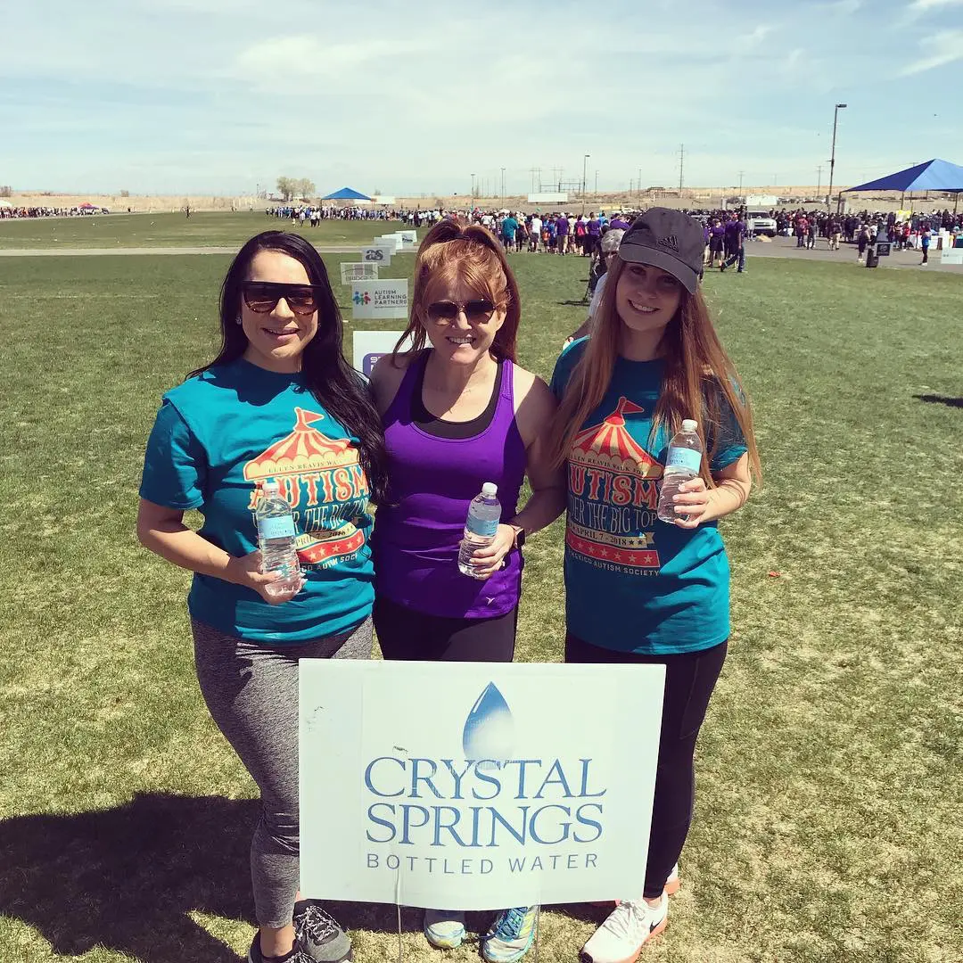 Three women standing in a field holding water bottles.